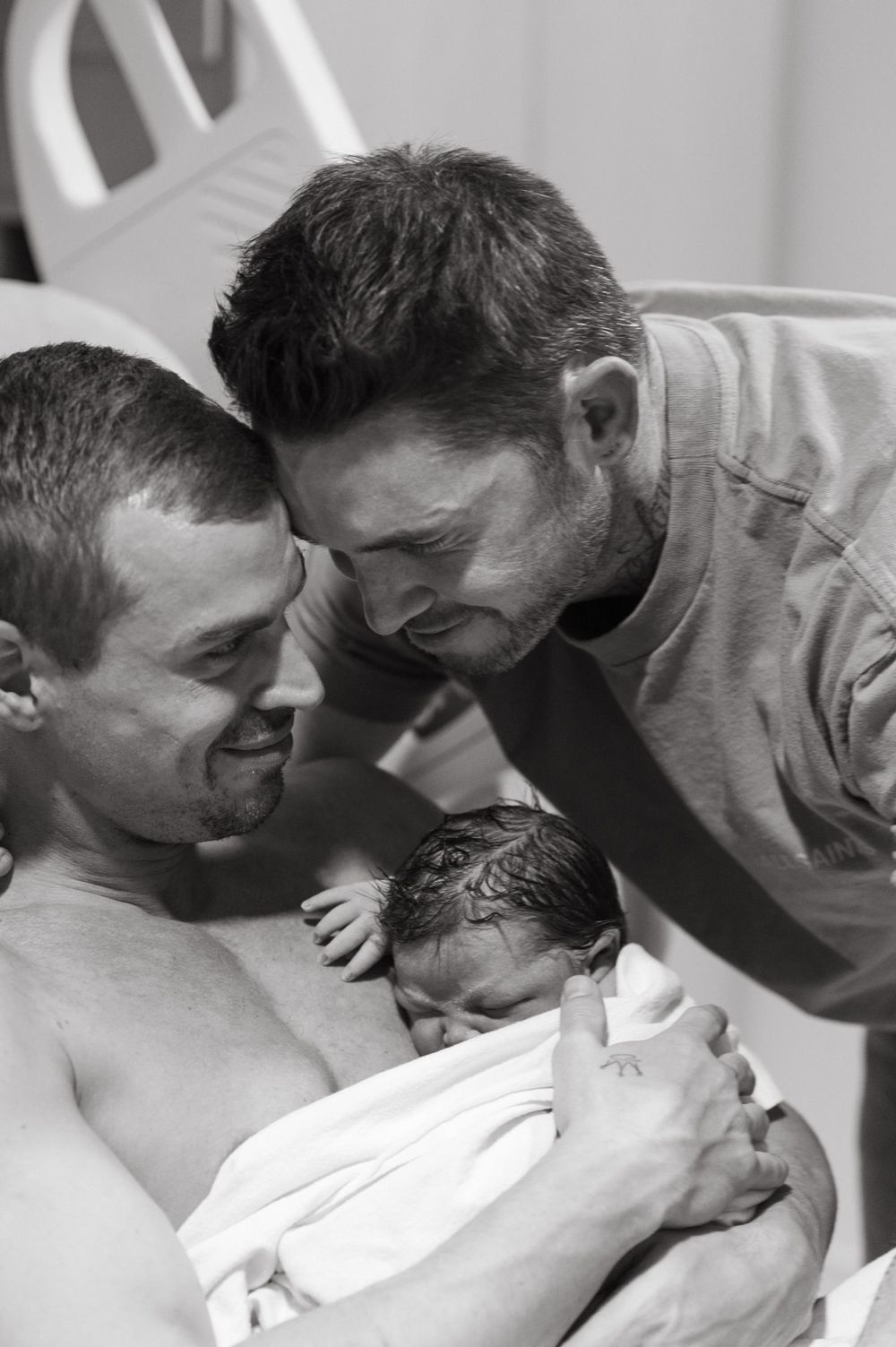 A touching black and white photograph capturing an intimate family moment with a newborn baby.
