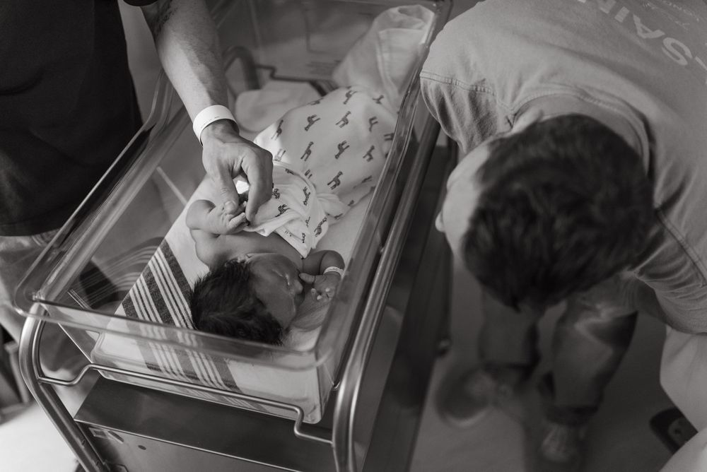 Black and white photos showing sequence of baby delivery and newborn care in a medical setting.