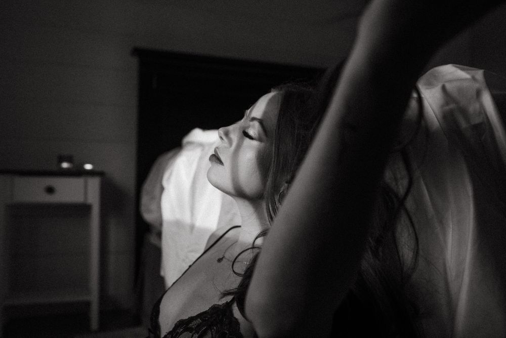 Black and white artistic portrait of a person resting with closed eyes in dark lighting.