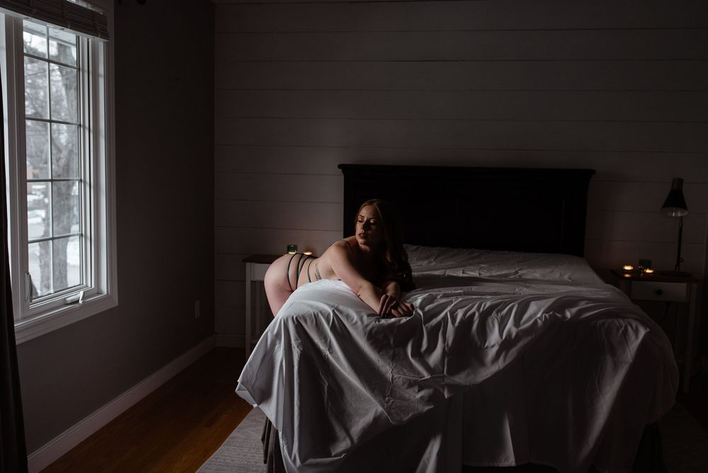 Atmospheric bedroom scene with white sheets and window light creating a moody ambiance.