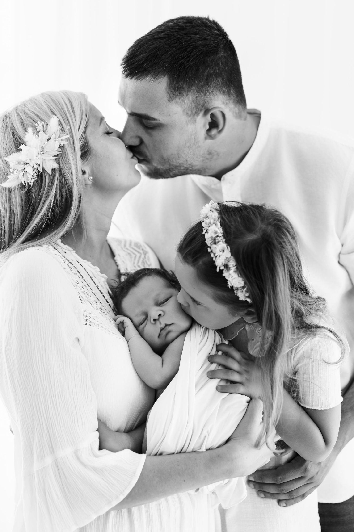 Four romantic black and white photos of couples kissing while dressed in light colored clothing.