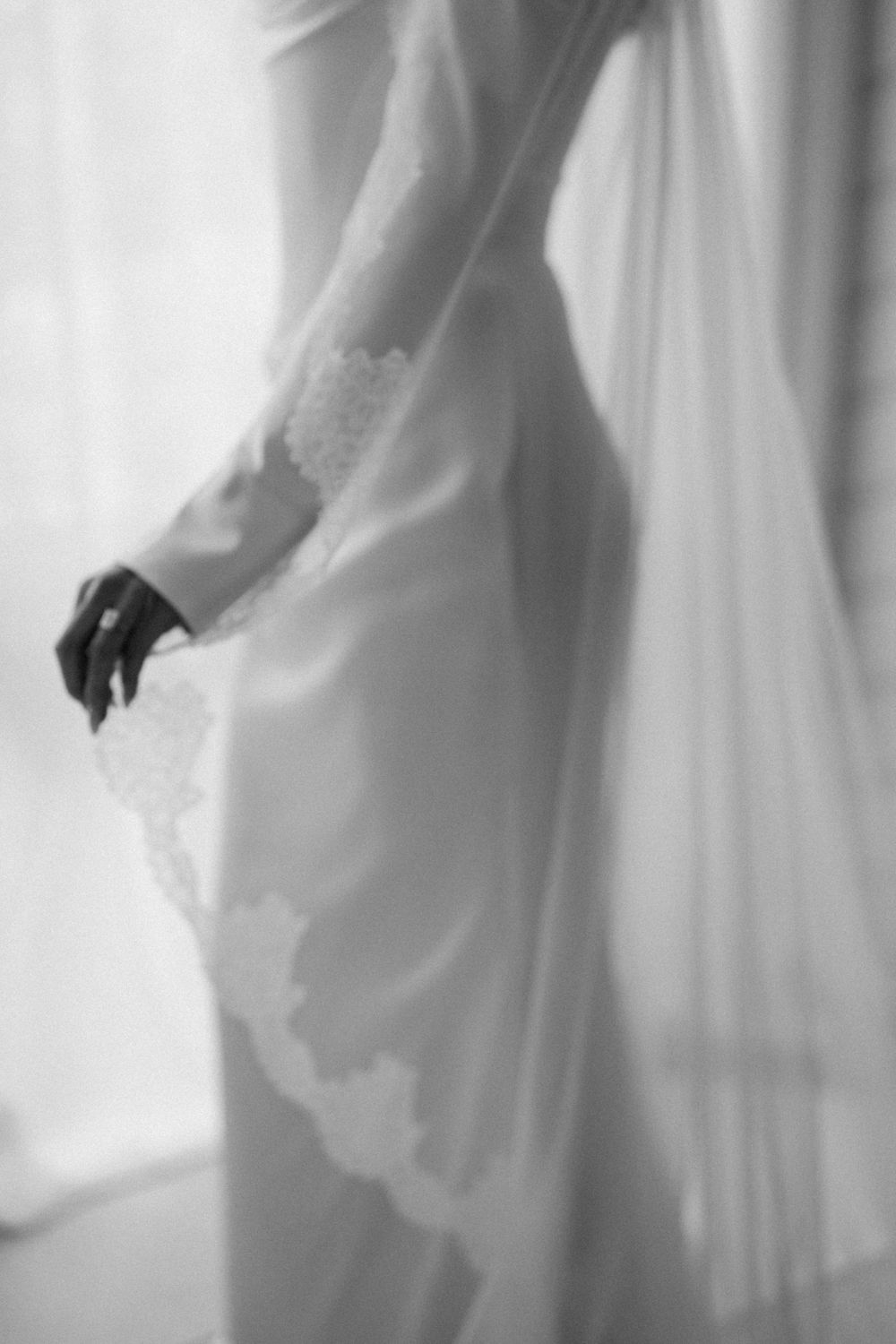 Ethereal series of flowing white wedding dress details shown in soft focus black and white photography.