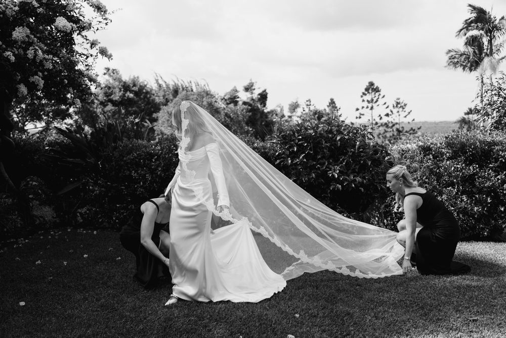 Black and white photo of a flowing wedding dress and veil being captured dramatically outdoors.