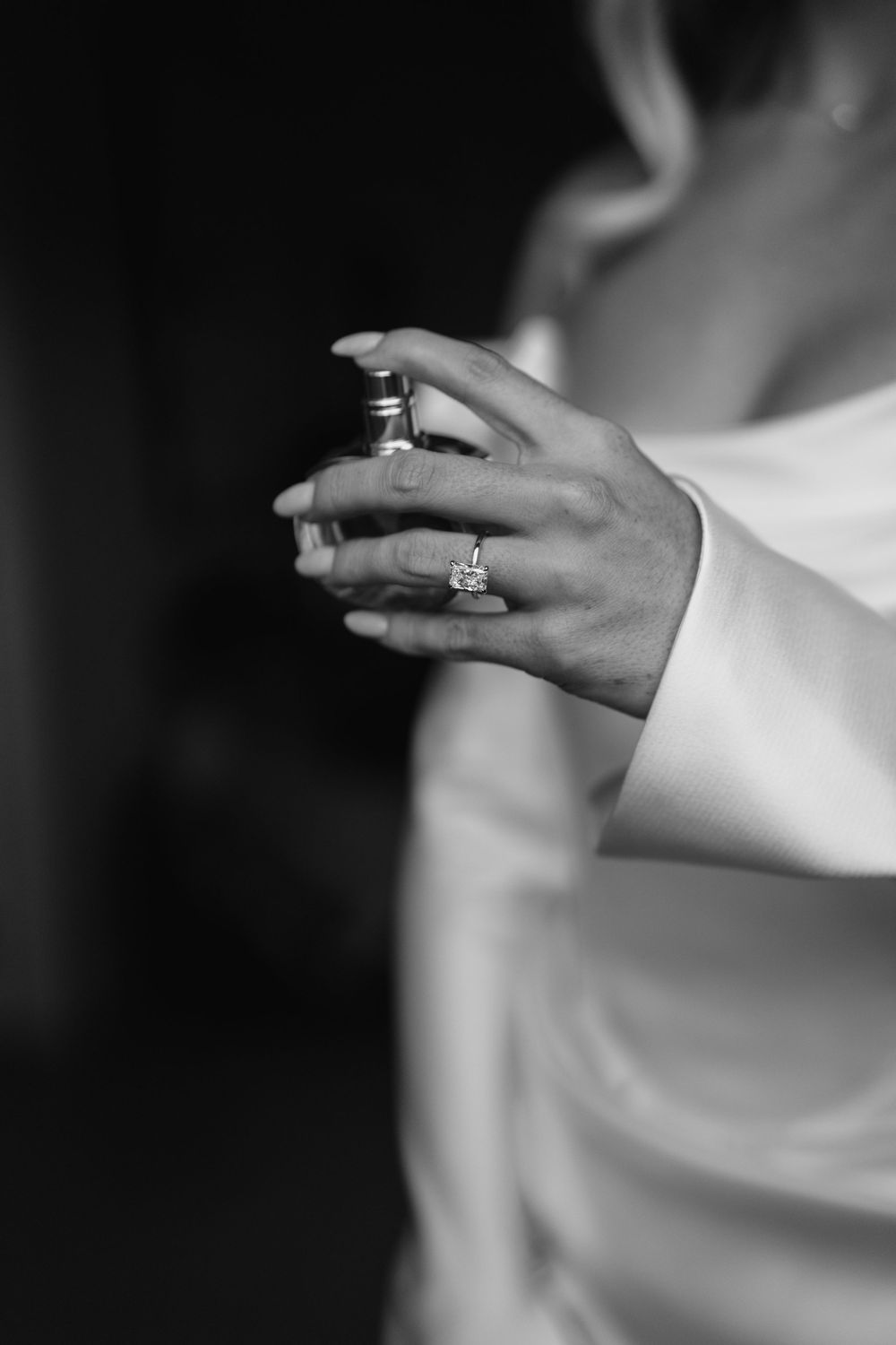 Close-up details of wedding rings and hands in black and white photography.
