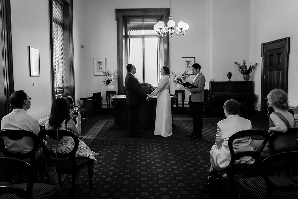 A series of black and white photos showing a couple's first look at an indoor venue with elegant lighting.