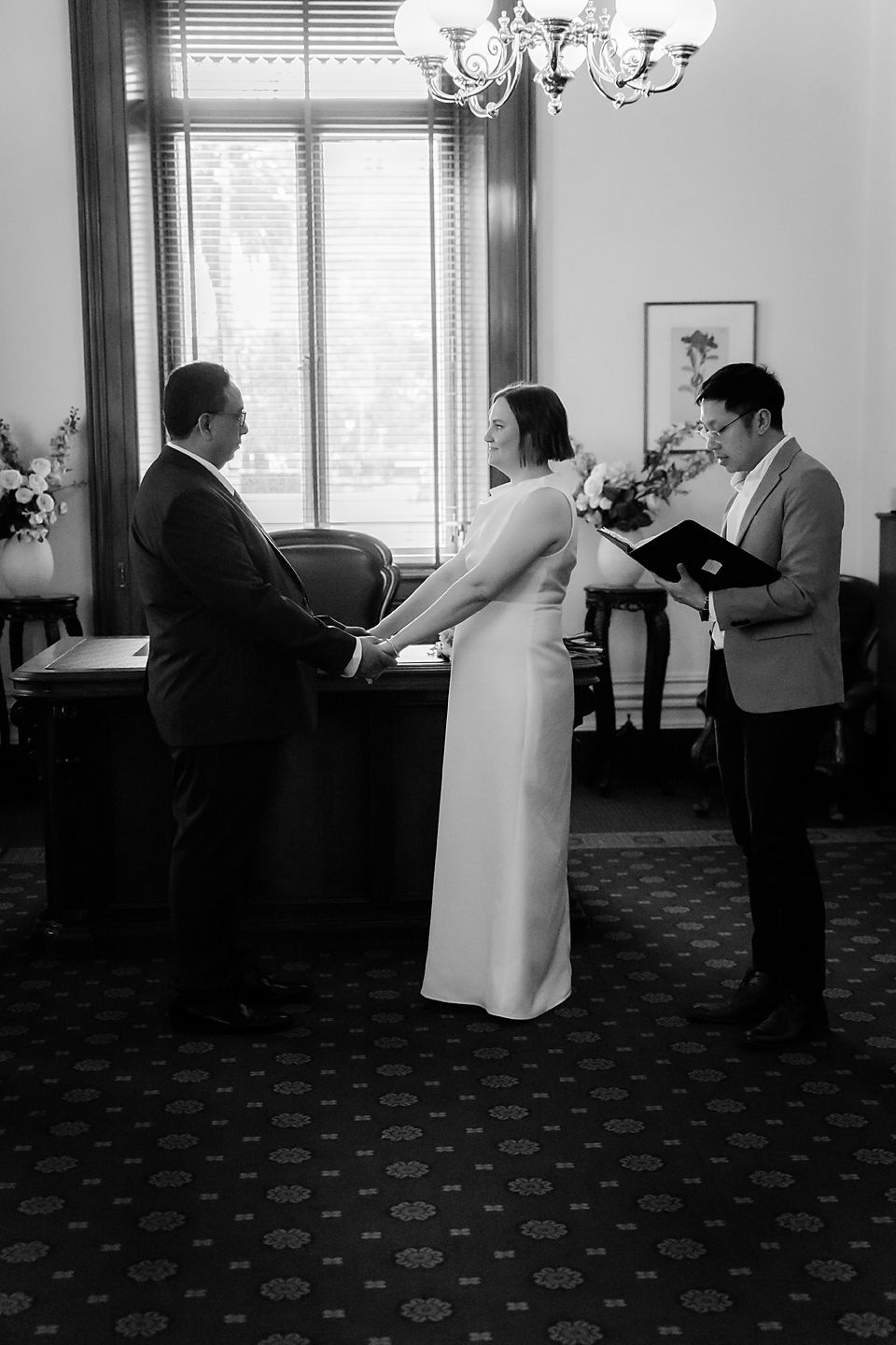 Black and white sequence showing a tender moment unfolding in an elegant room with chandelier lighting.