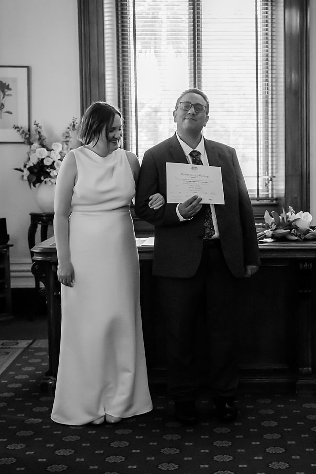 Black and white photos capturing intimate moments in a formal indoor setting with window light.