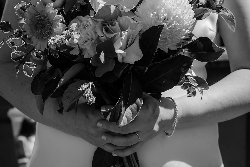 Black and white photograph showing multiple flower arrangements being prepared on a workspace.