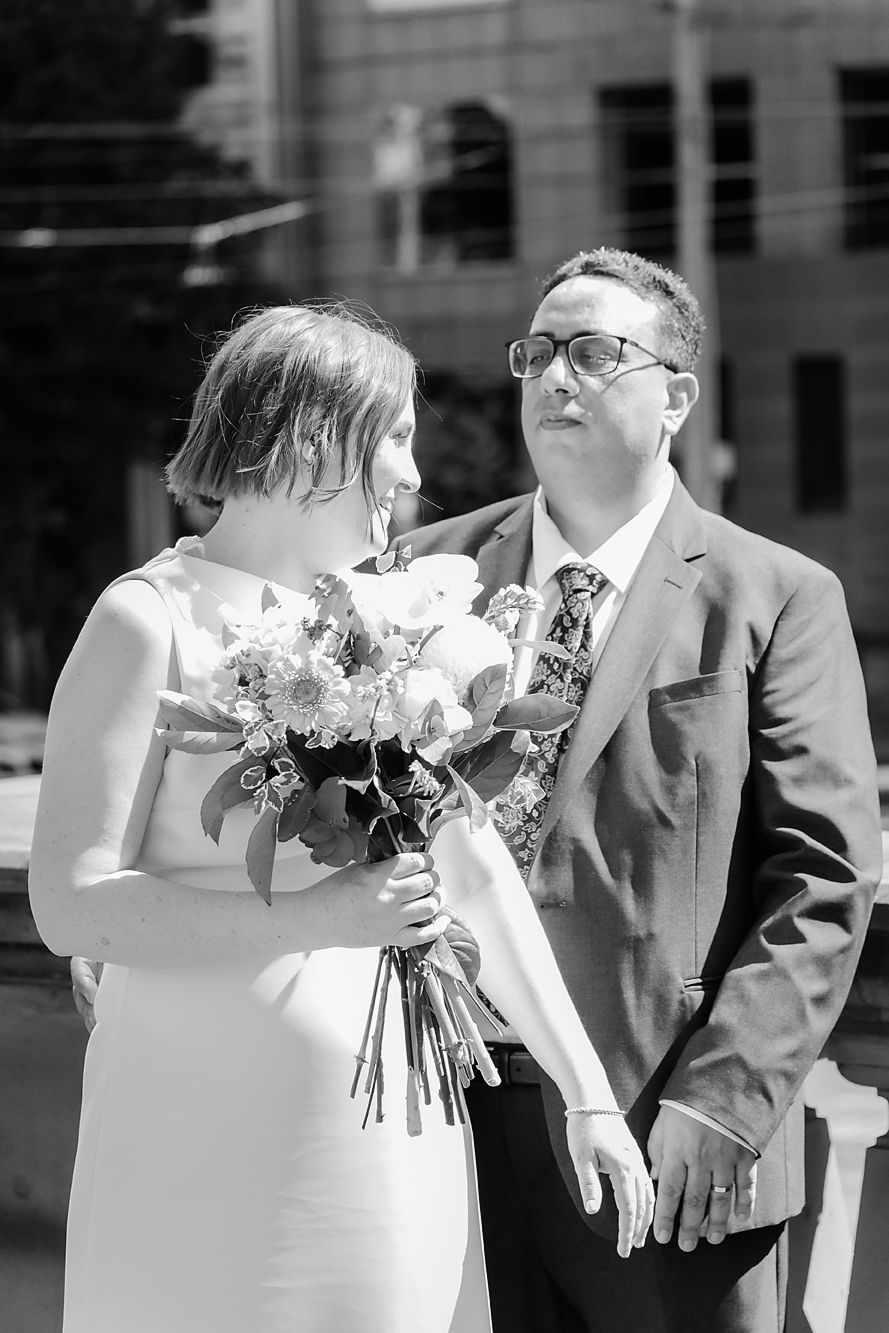 Four progressive black and white photos show a couple in wedding attire sharing a romantic kiss outdoors.