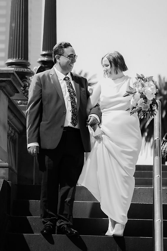 Black and white dynamic wedding sequence showing couple dancing playfully on outdoor stone steps.