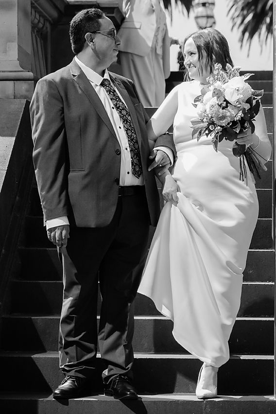 Black and white wedding photos showing couple on steps with romantic poses contrasting white dress and dark suit.