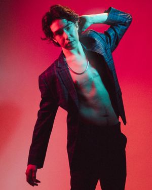 Artistic portrait shot against red background with dramatic teal lighting casting moody shadows and silhouettes.