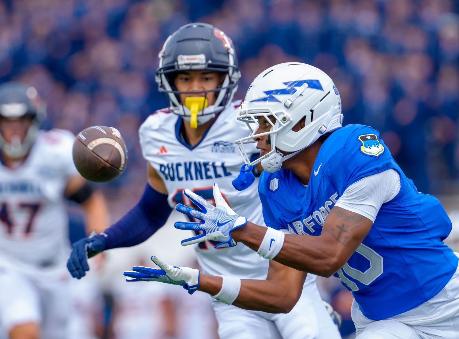 Football player makes a diving catch attempt in a blue and white uniform during a competitive game.