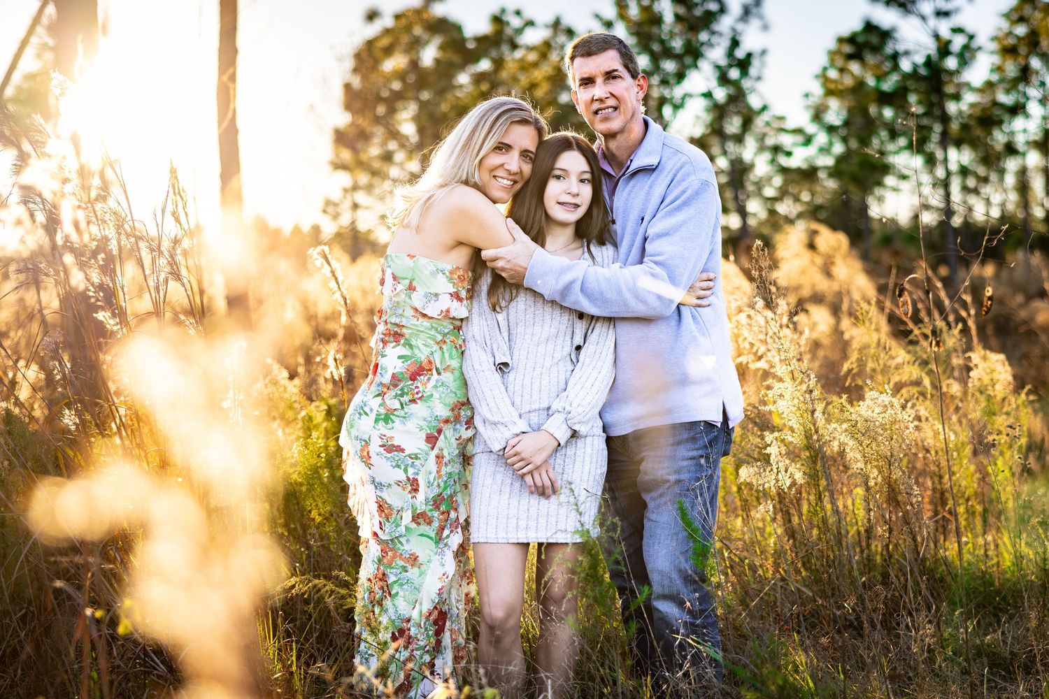 Couple shares tender moments in a sun-drenched meadow during evening golden hour photo session at sunset.