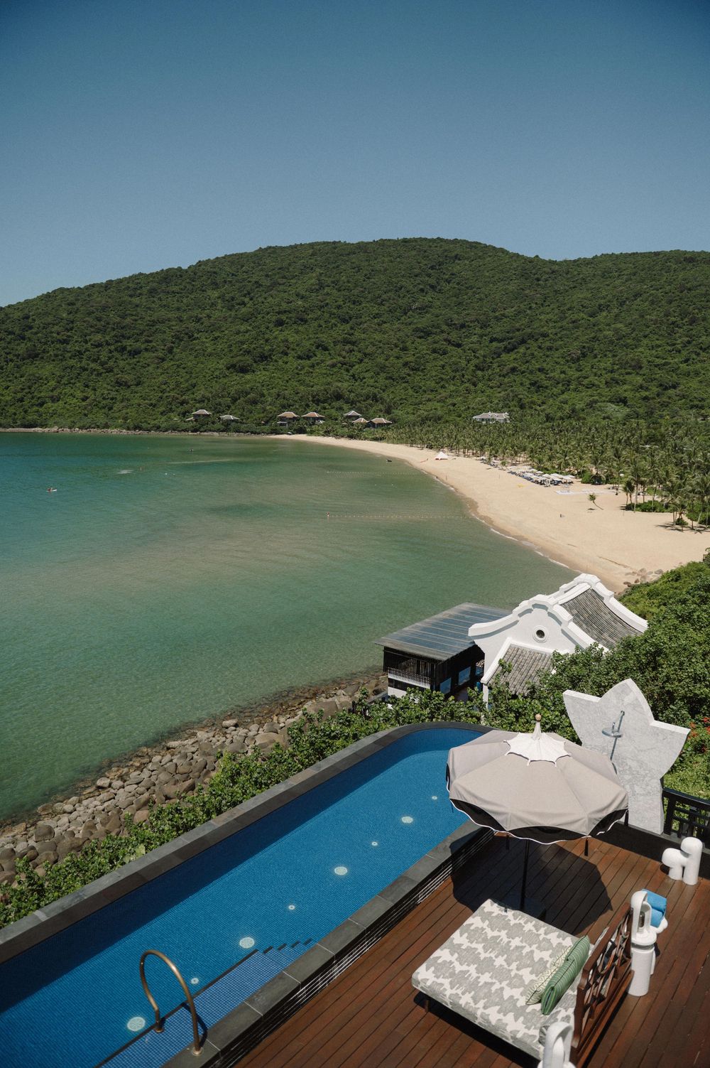 Aerial view of a luxury beachfront venue with infinity pool and white beach chairs.