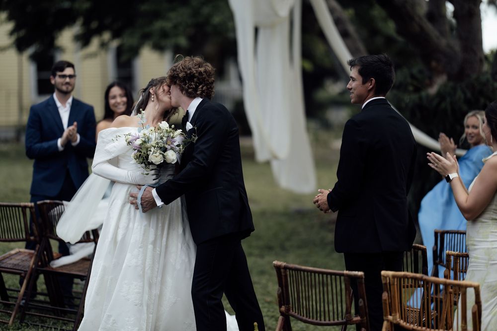 Wedding ceremony guests gather outdoors on a sunny day as the couple exchanges vows.