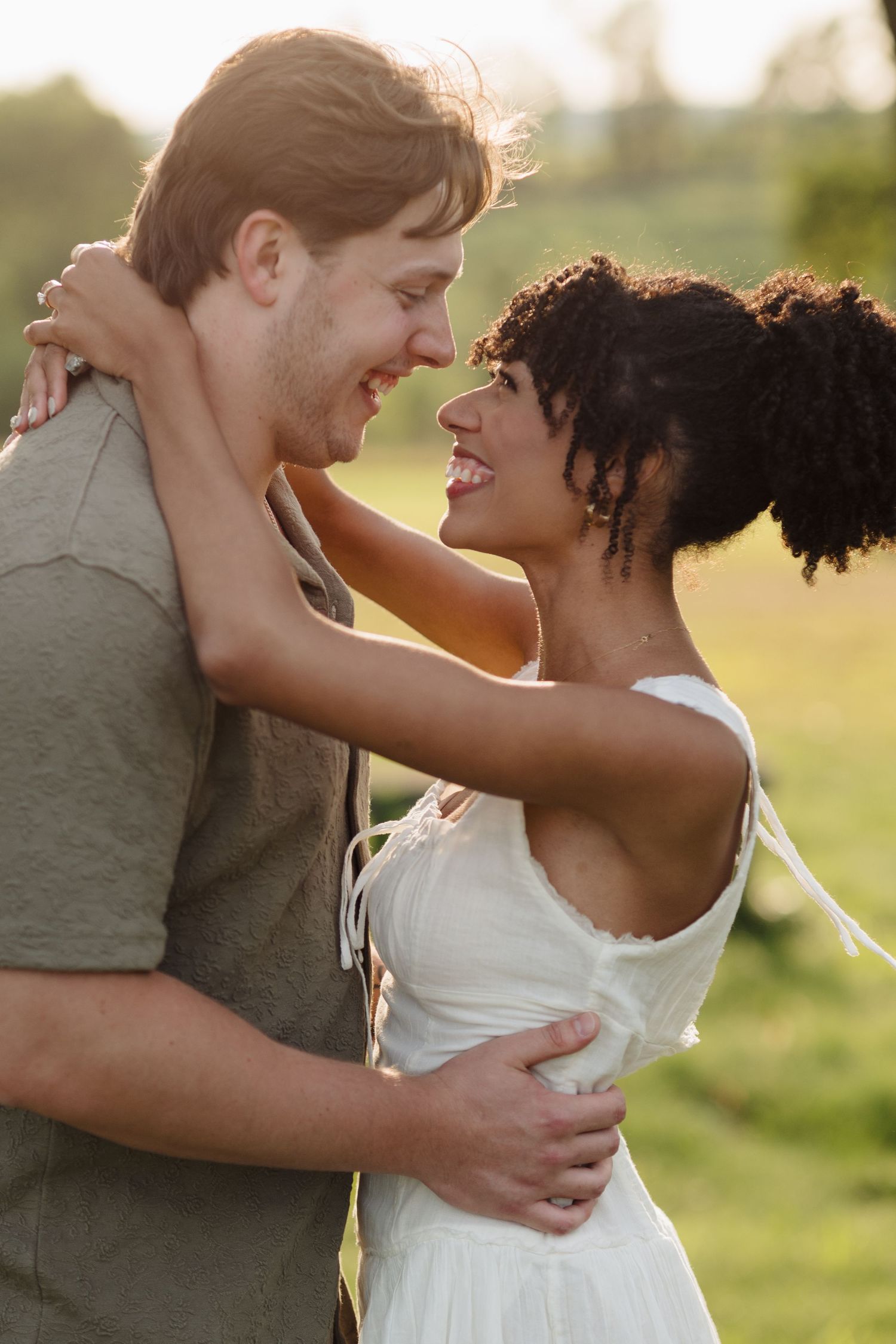 Intimate couple sharing tender moments in a sun-lit meadow during golden hour.