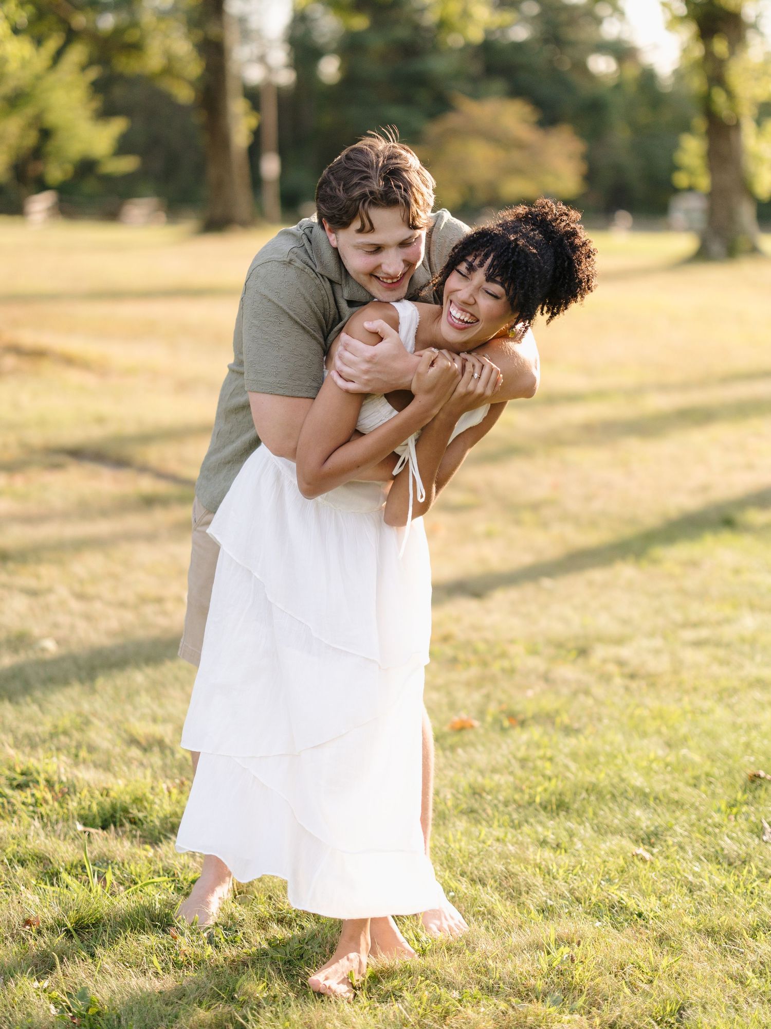 Playful couple shares joyful moments together in a sun-drenched summer field.