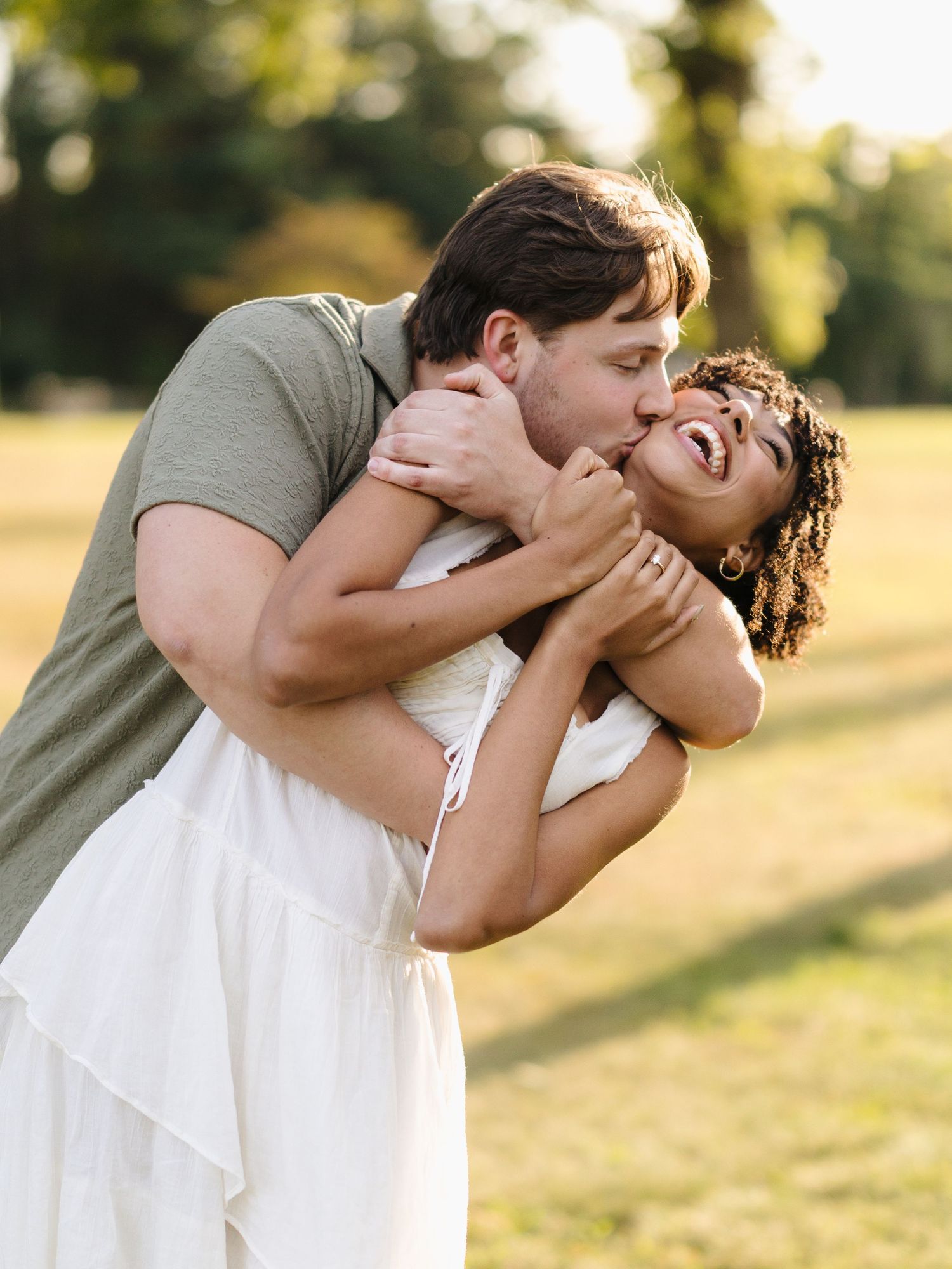 Couple embracing and sharing passionate moments outdoors in warm sunlight.