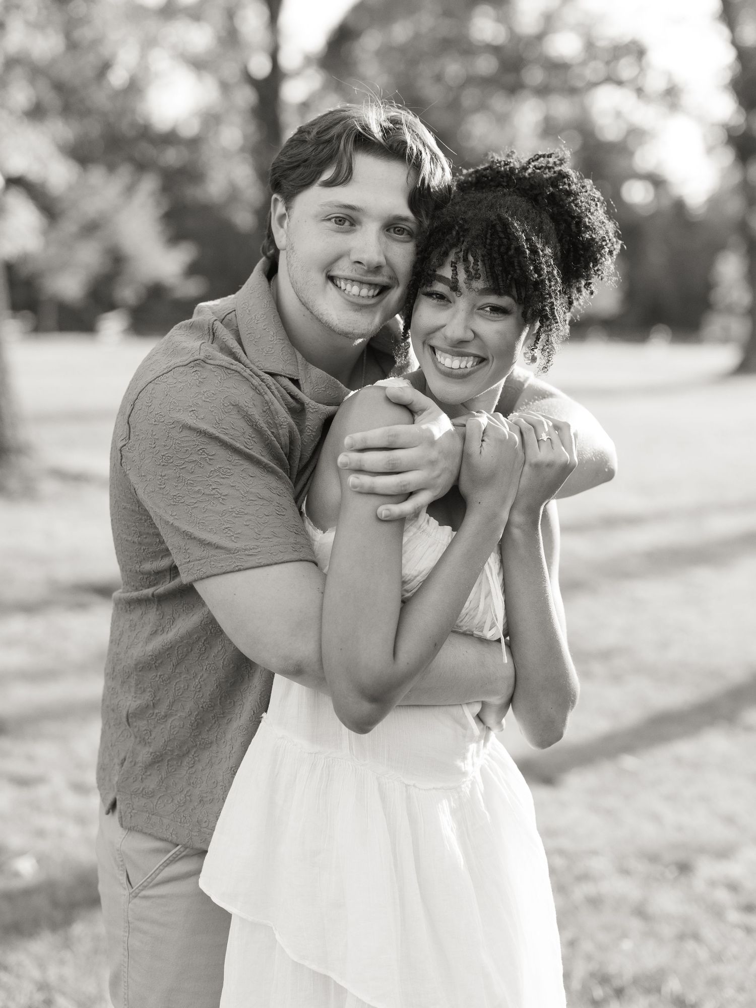 Black and white photo series capturing playful moments between a couple in a park setting.