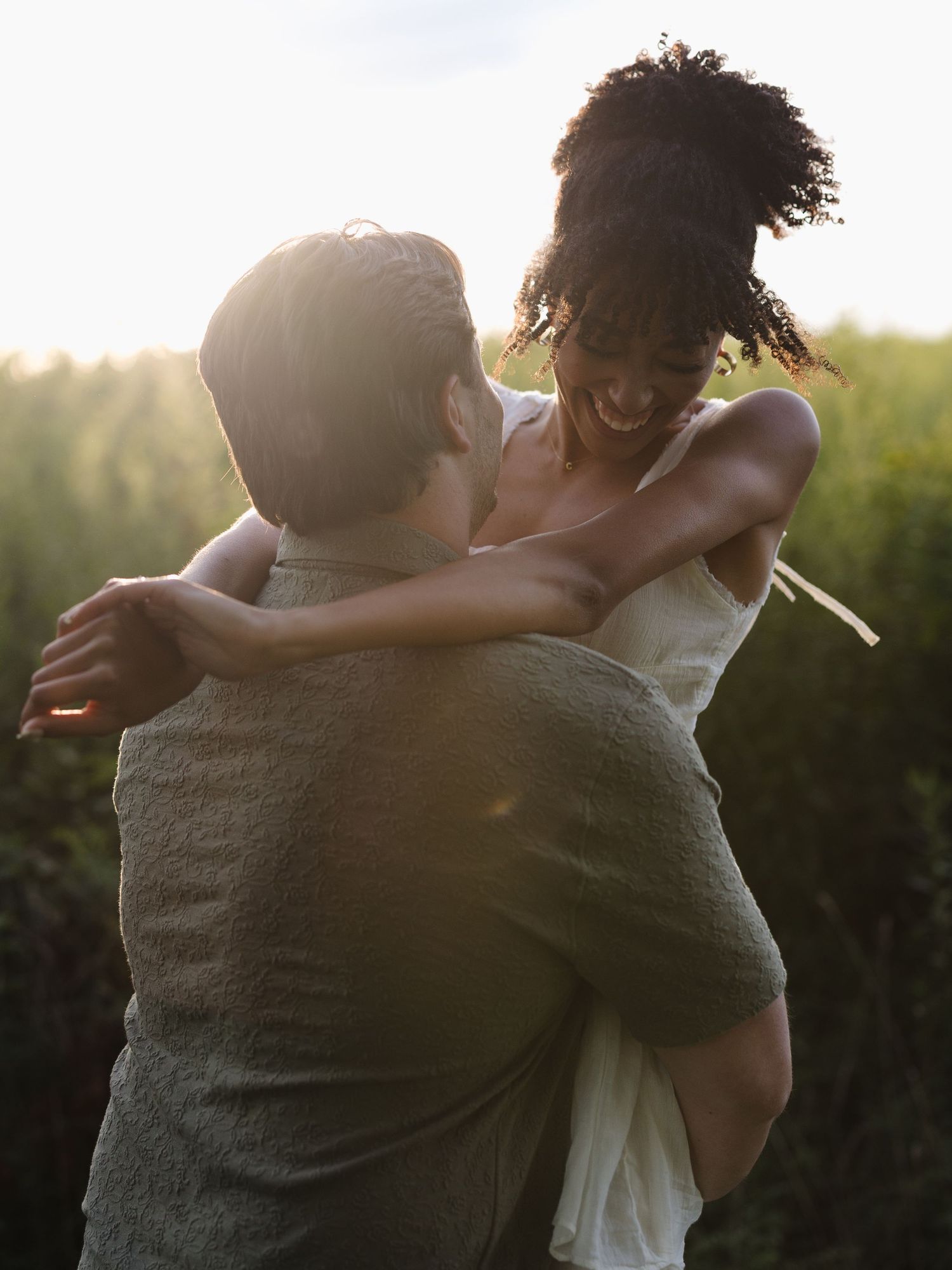Silhouetted couple embracing during golden hour in a natural outdoor setting.