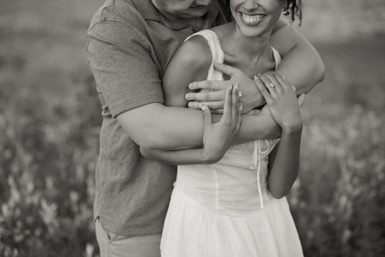 A joyful couple shares a candid moment while embracing in a wildflower field.