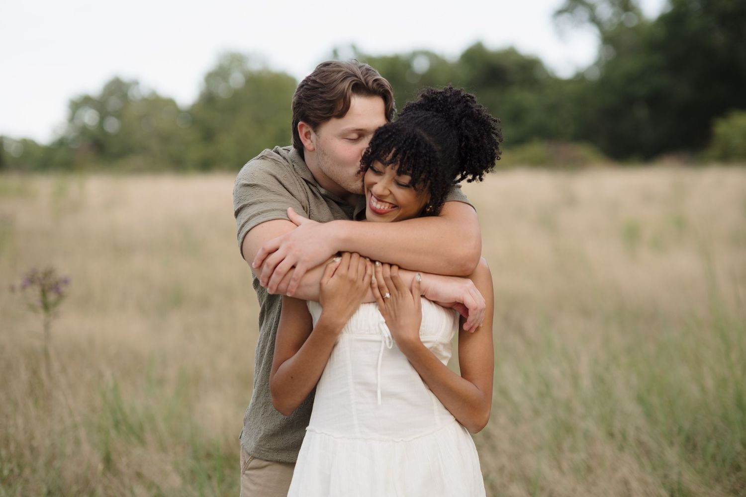 Romantic couple sharing intimate moments while posing together in a natural field setting.