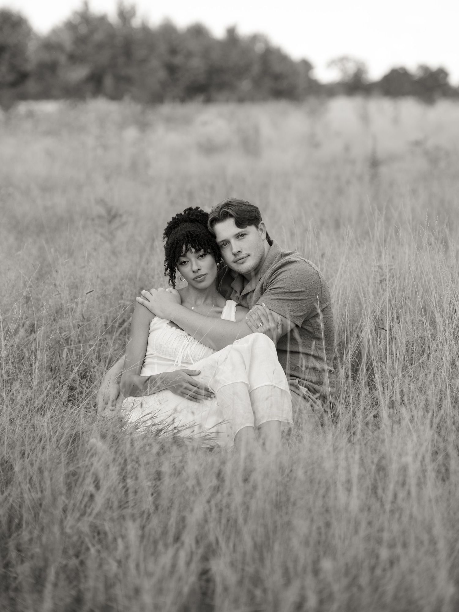 Black and white photo of a couple lying together in tall grass.