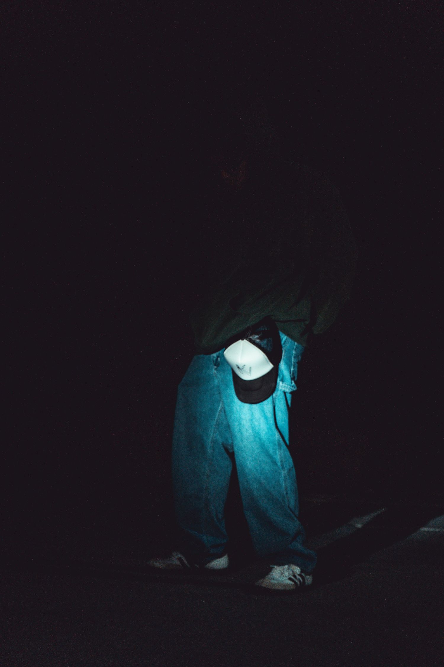 Dramatic blue lighting illuminates figure in dark environment.
