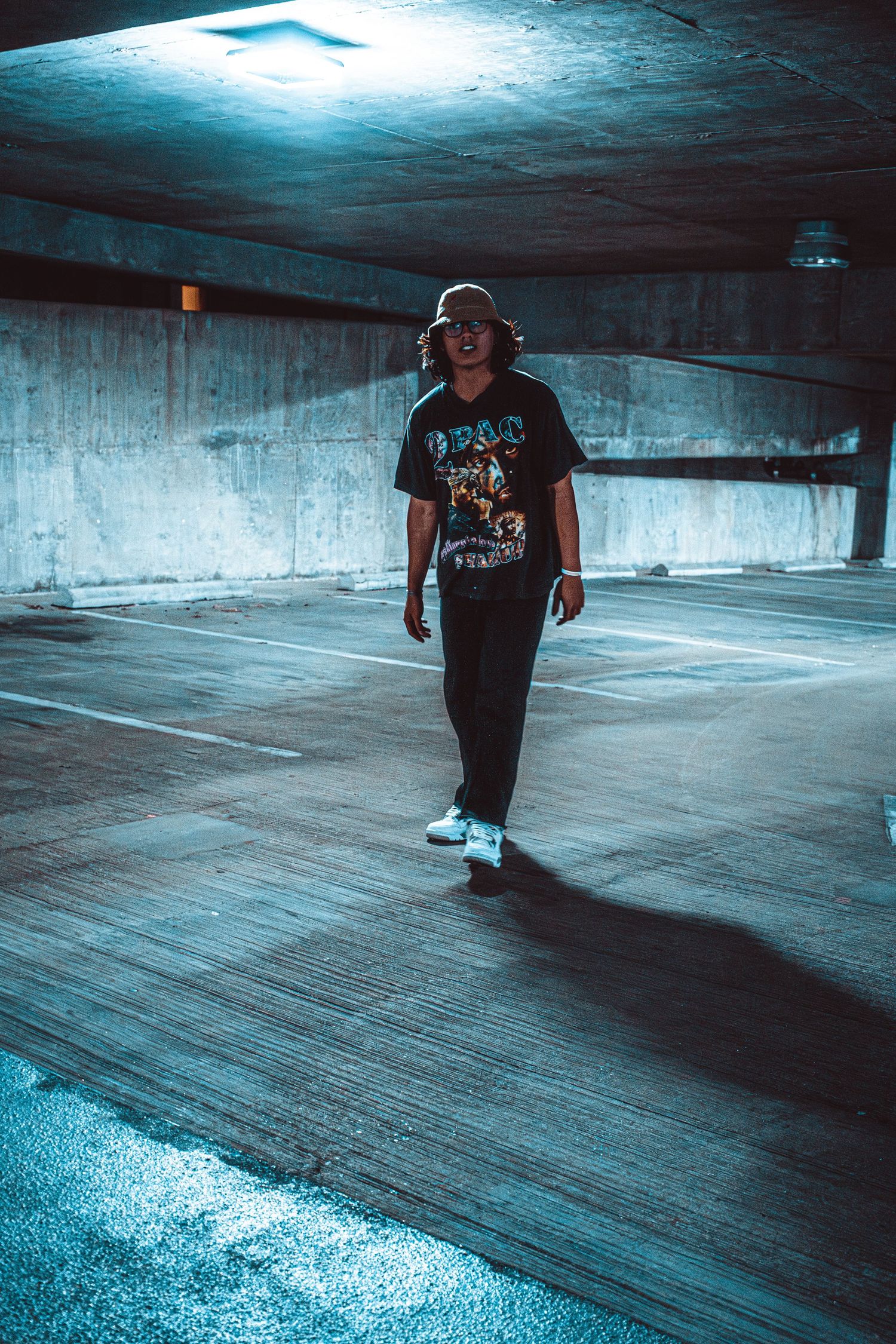 Person moving through empty parking garage with dramatic blue lighting effects.