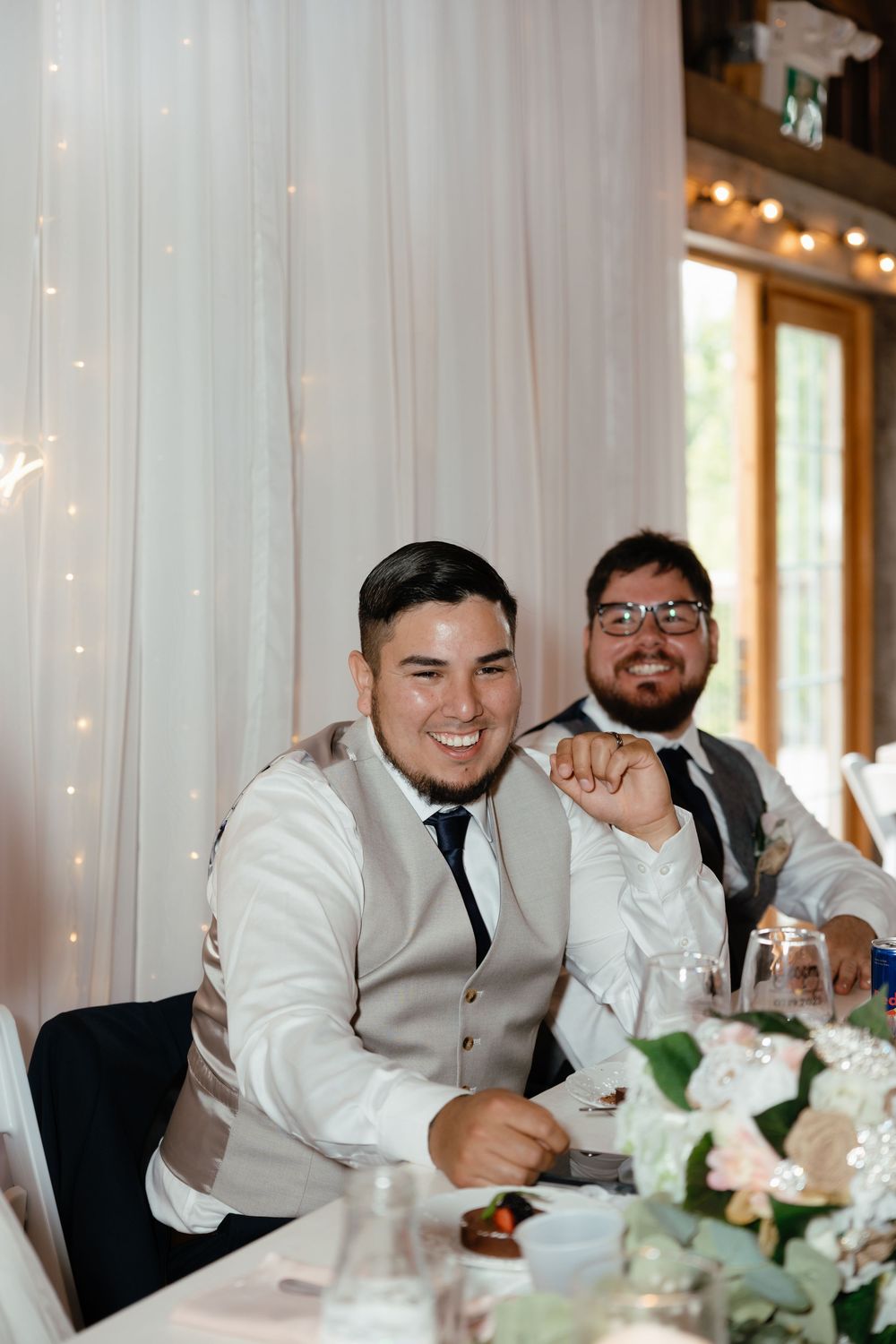 Guests enjoying themselves at an elegant wedding reception banquet with white table decor and string lights.