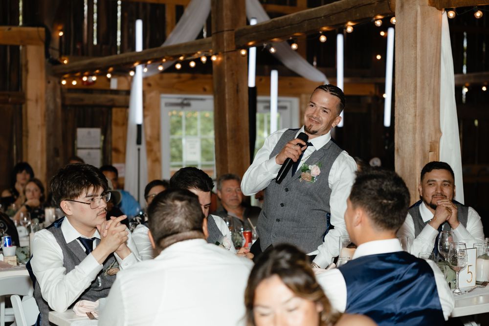 Wedding guests raise their glasses in celebration at an elegant indoor reception venue with warm lighting.
