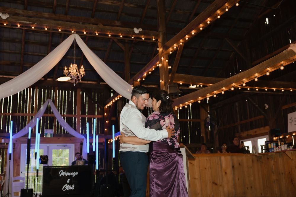A romantic rustic barn reception venue decorated with string lights and white fabric draping over the dance floor area.