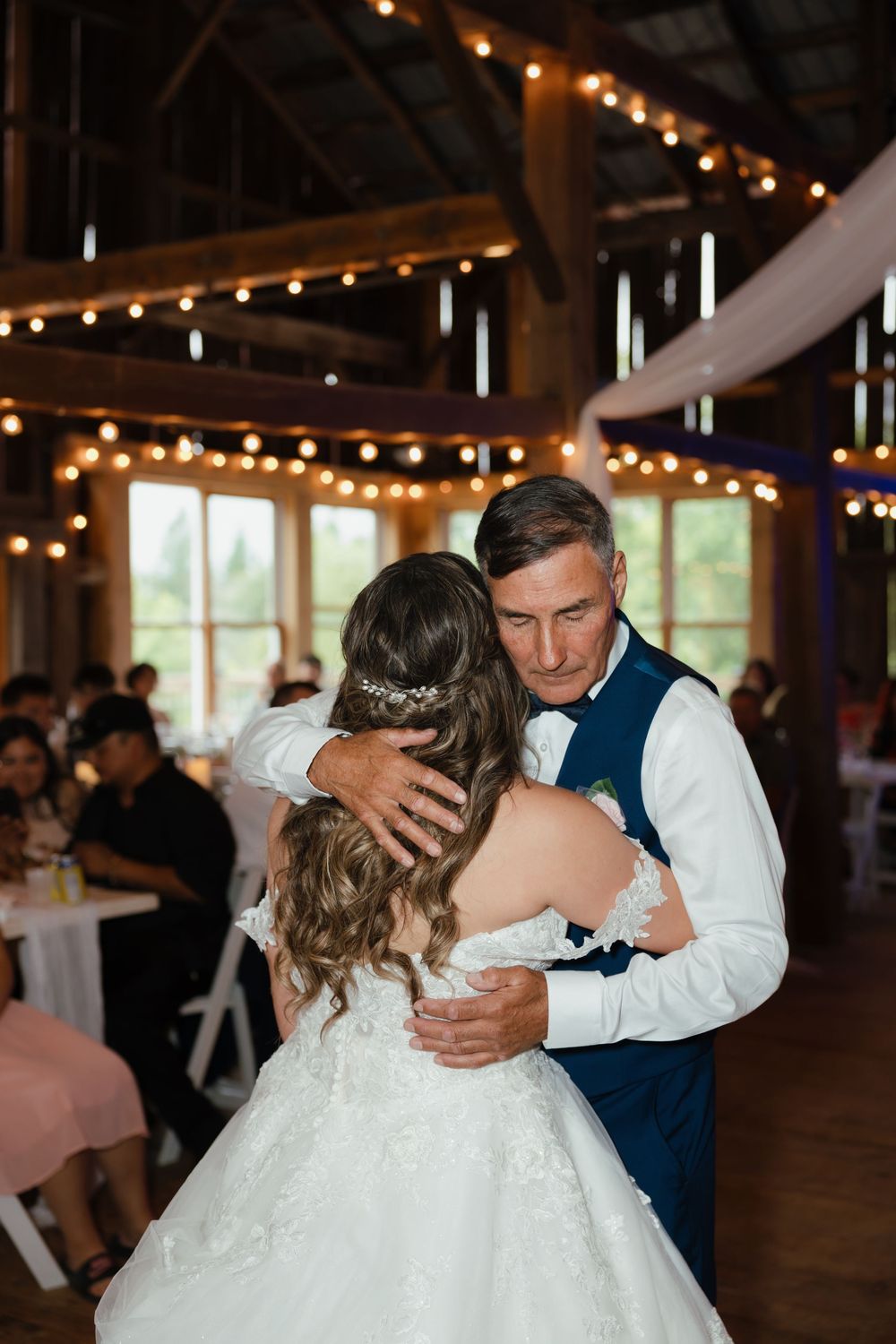 A romantic series of wedding dance moments captured in a rustic barn venue illuminated by warm string lights.