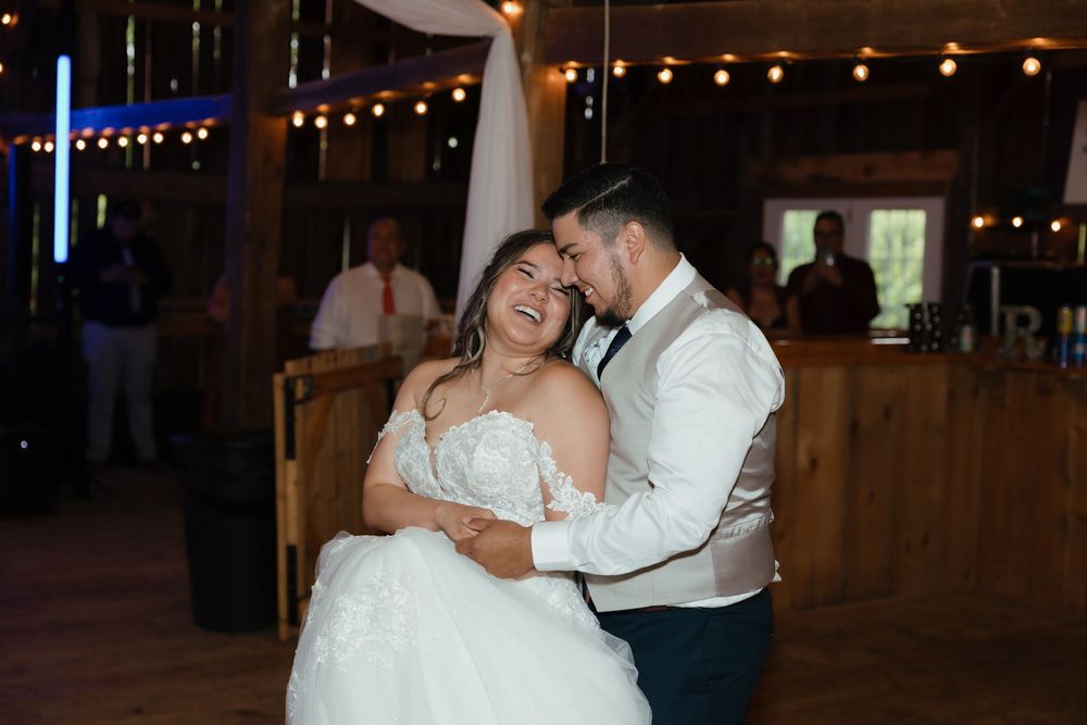 Dancing couple at wedding reception under warm lighting and decorative drapes.