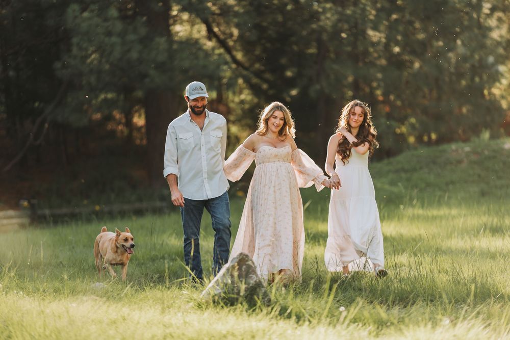 A family walks together through a sunlit meadow during golden hour.