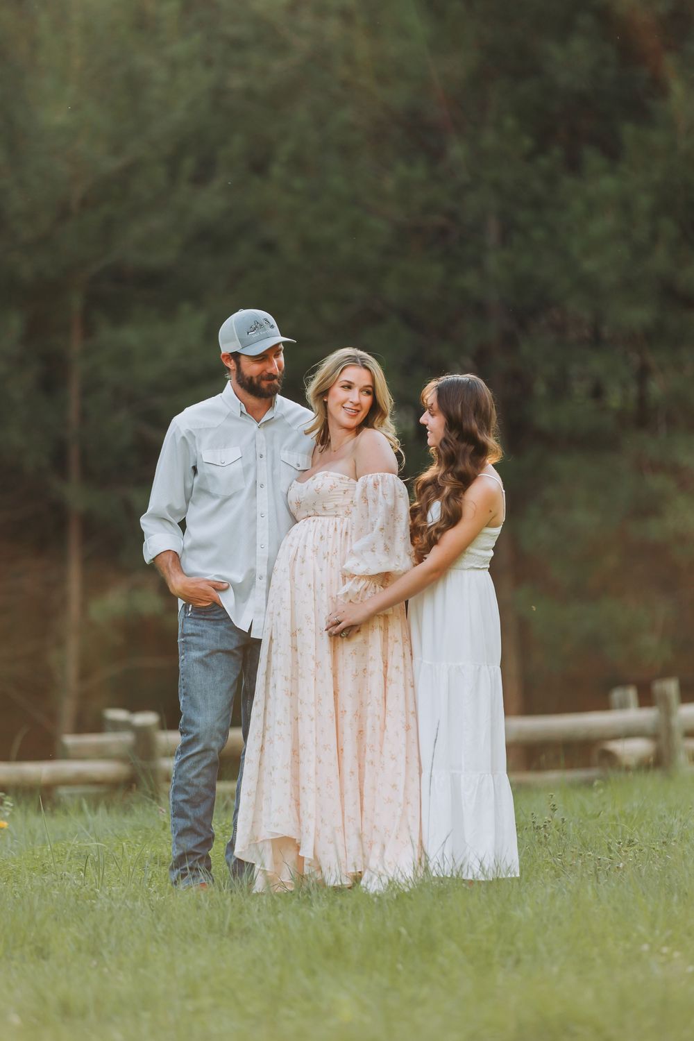 A family shares tender moments together in a grassy field on a peaceful summer evening.
