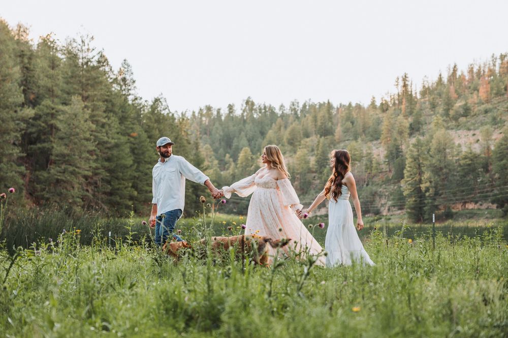 People enjoying a beautiful summer day in a meadow surrounded by evergreen trees and wildflowers.