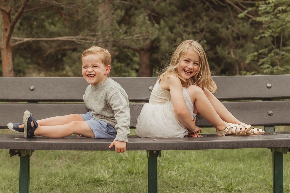 Family having fun posing on wooden park bench surrounded by greenery.