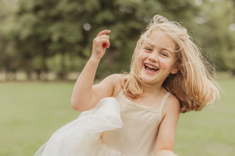 Person with blonde hair laughing joyfully outdoors in natural setting.