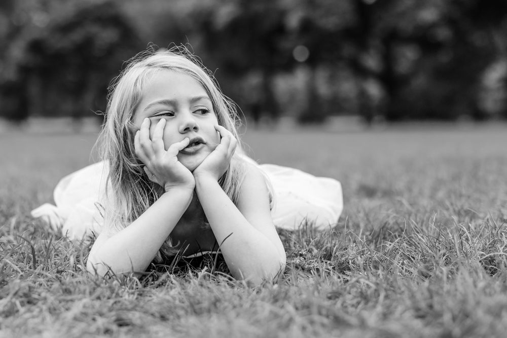 People lying in grass during outdoor photo session in black and white.