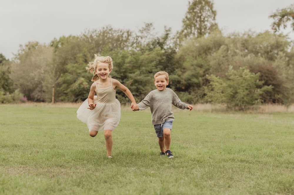 Children running and playing together in a green outdoor setting.