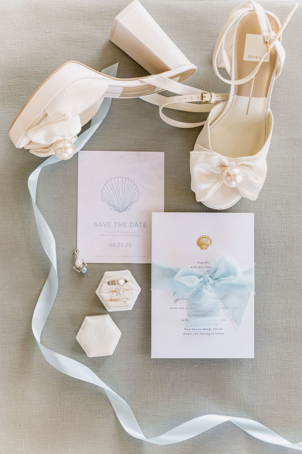 Elegant wedding invitation suite with watercolor details and light blue ribbons on gray linen.