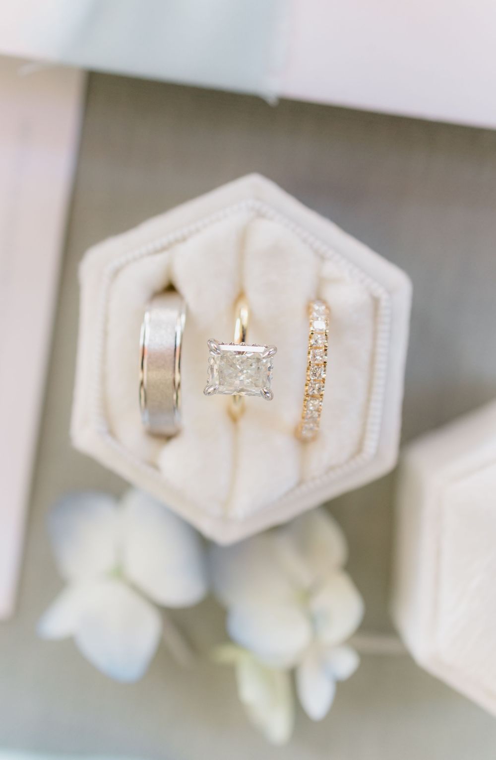 Wedding rings and jewelry displayed on white hexagonal holders.