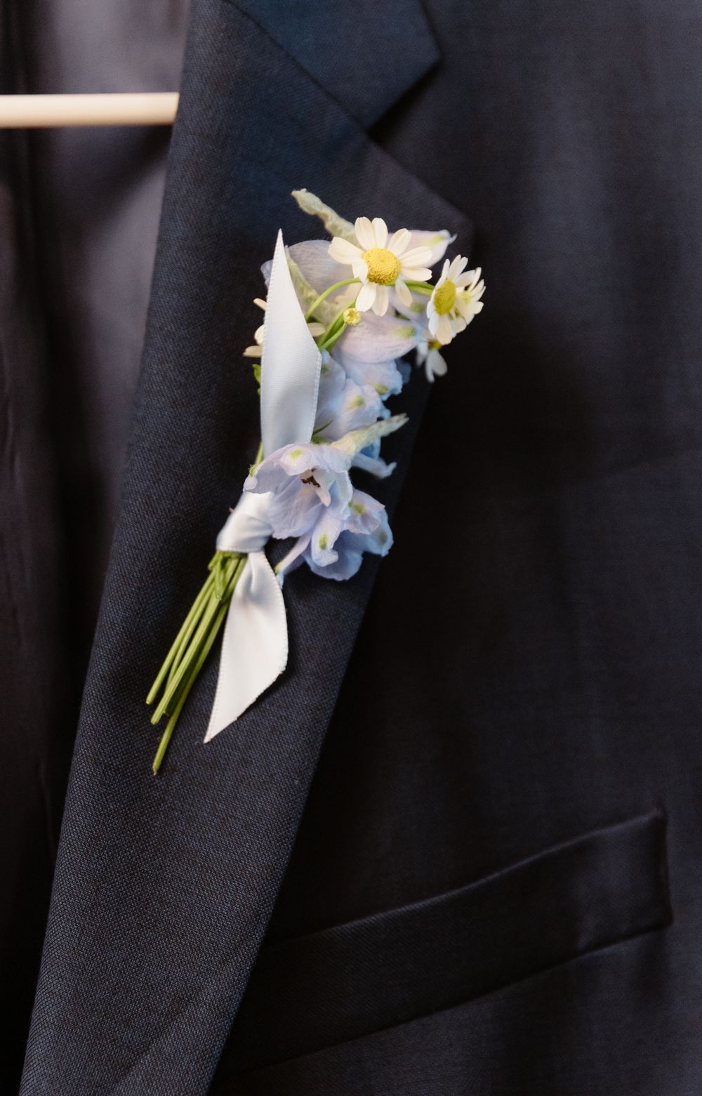 Light blue and white floral boutonnières pinned to dark suits.