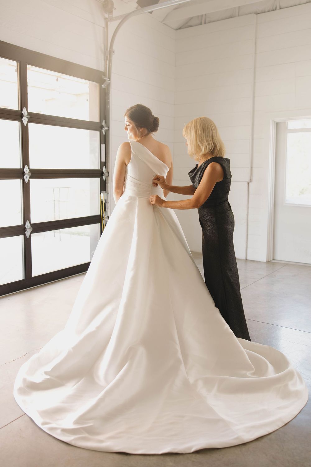 Series of photos showing the arrangement of a flowing white wedding dress train in a bright studio space.