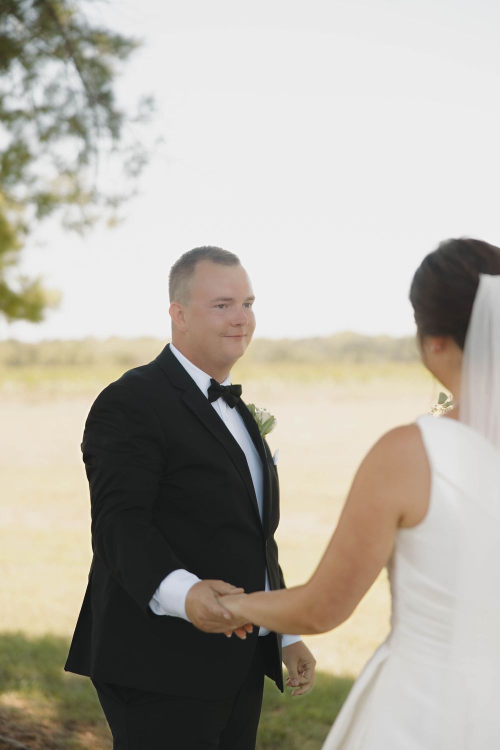 Wedding couple sharing a tender moment in an outdoor field with soft lighting.