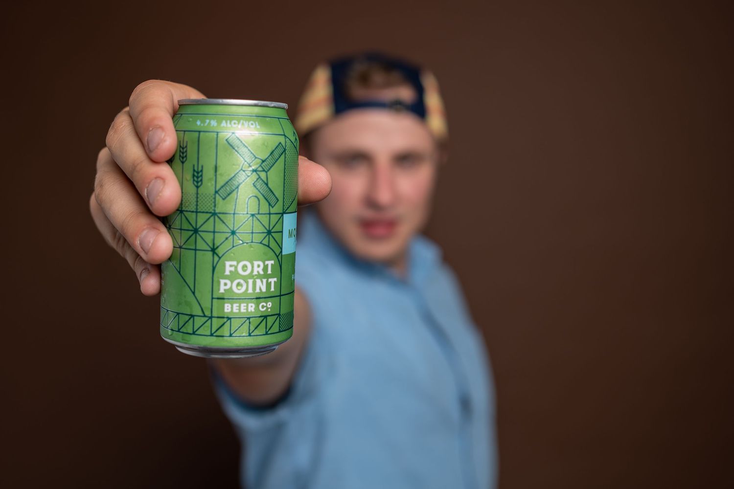 Lifestyle product photo of a craft beer can held toward the camera, subject blurred — Portland commercial photography.