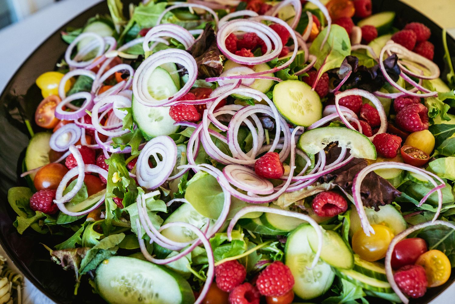 Colorful mixed salad with red onion, cucumber, and strawberries — commercial food photography, Portland.