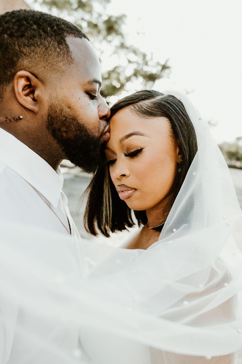 A romantic couple shares tender moments in a series of white-themed intimate portraits outdoors.